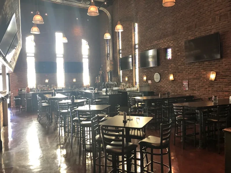 Modern industrial bar interior featuring brick walls and high-top tables.