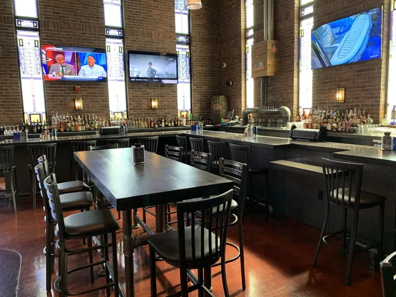 Industrial-chic bar interior with brick walls, long counter, high table.