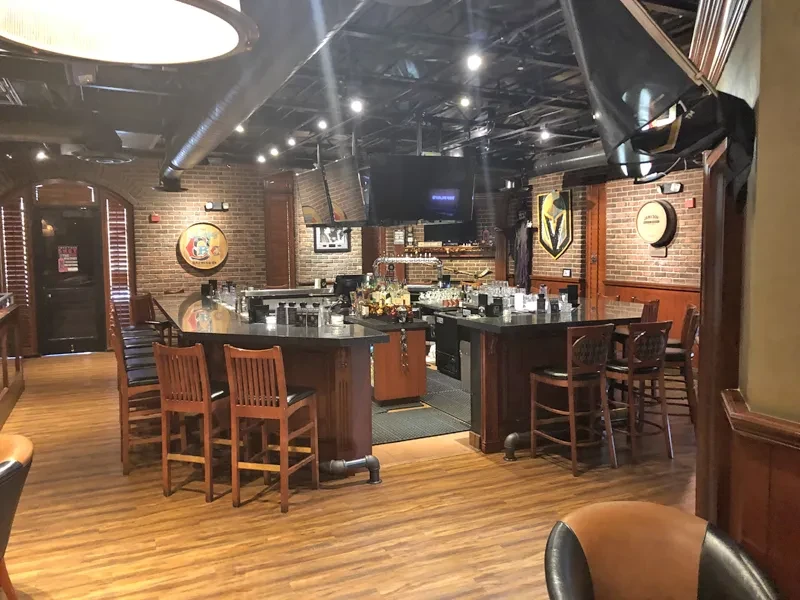 Empty pub interior with a large U-shaped bar and brick walls.