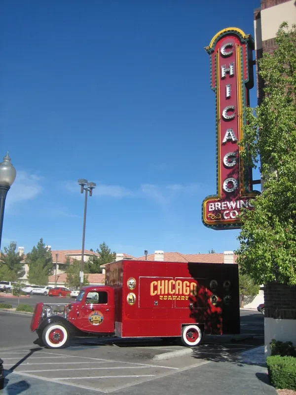 Vintage red Chicago Brewing Company truck parked by its neon sign.