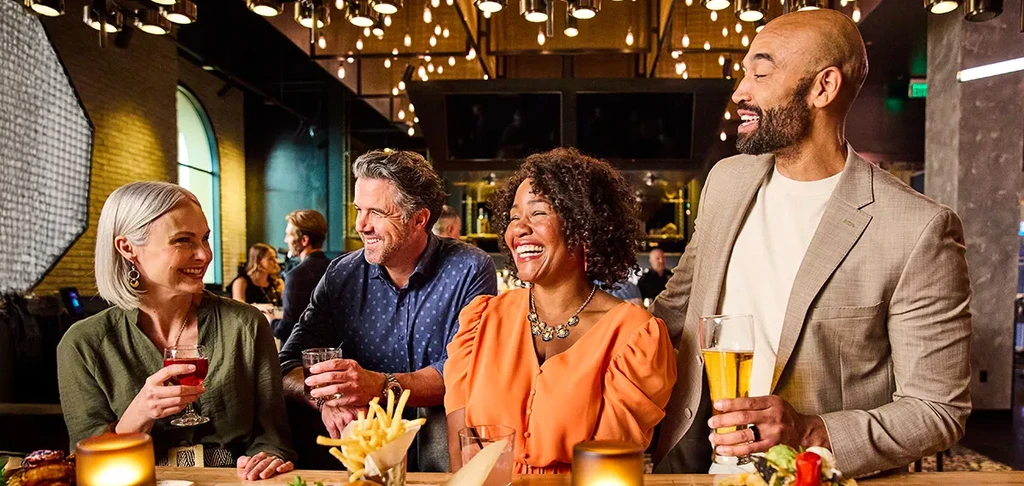 Four people enjoying drinks and food at a lively modern bar.