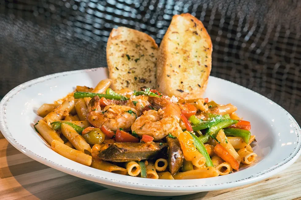 Penne pasta with shrimp, vegetables, red sauce, and garlic bread.