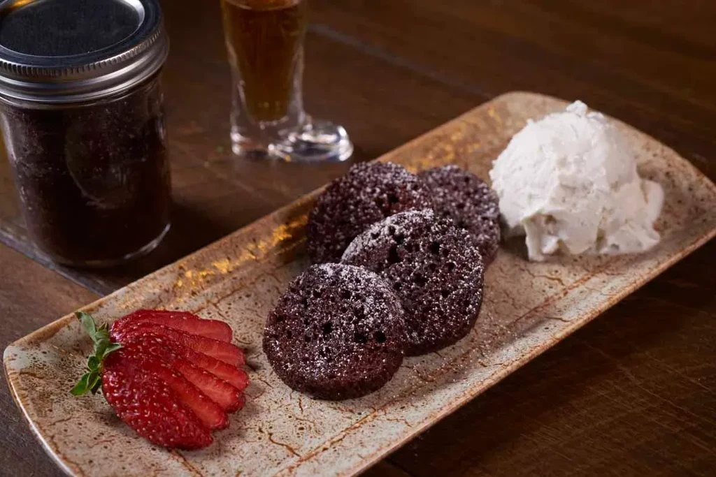 Dessert platter with four powdered sugar cakes, strawberry, and ice cream.