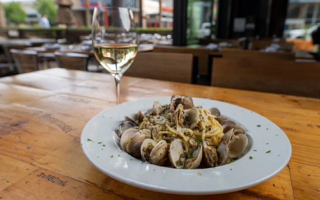 Plate of pasta with clams and white wine on a rustic table.