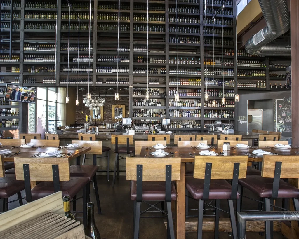 Restaurant interior with vast wine wall, dining tables, and bar.