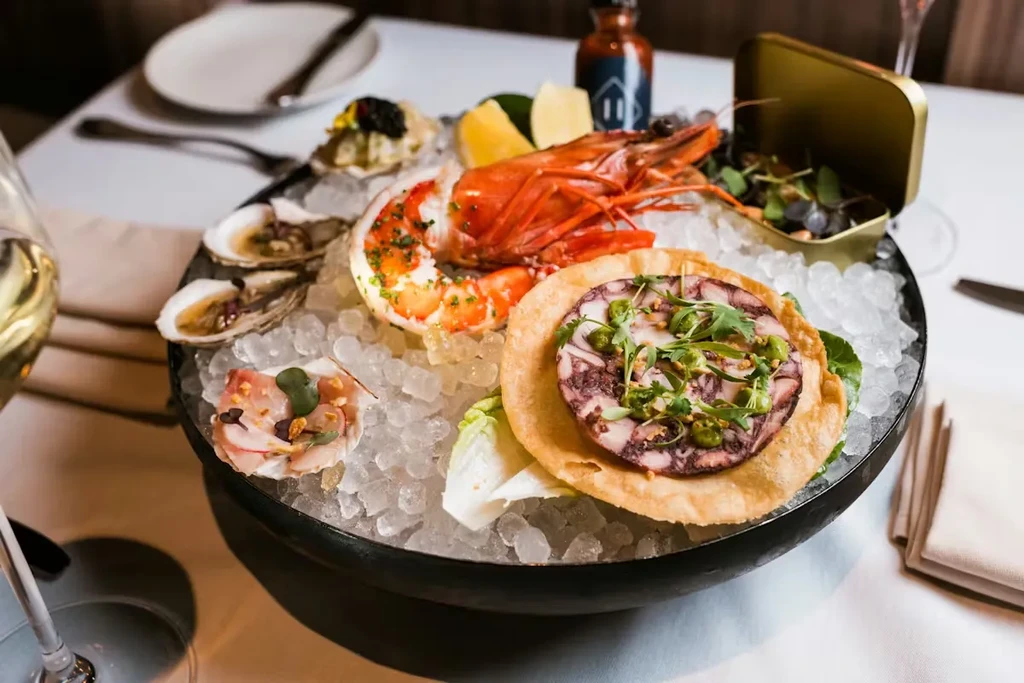 Elaborate seafood platter with lobster, oysters, shrimp, and terrine on crushed ice.