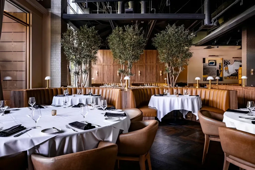Modern dining room with round tables, brown leather booths, and wood walls.