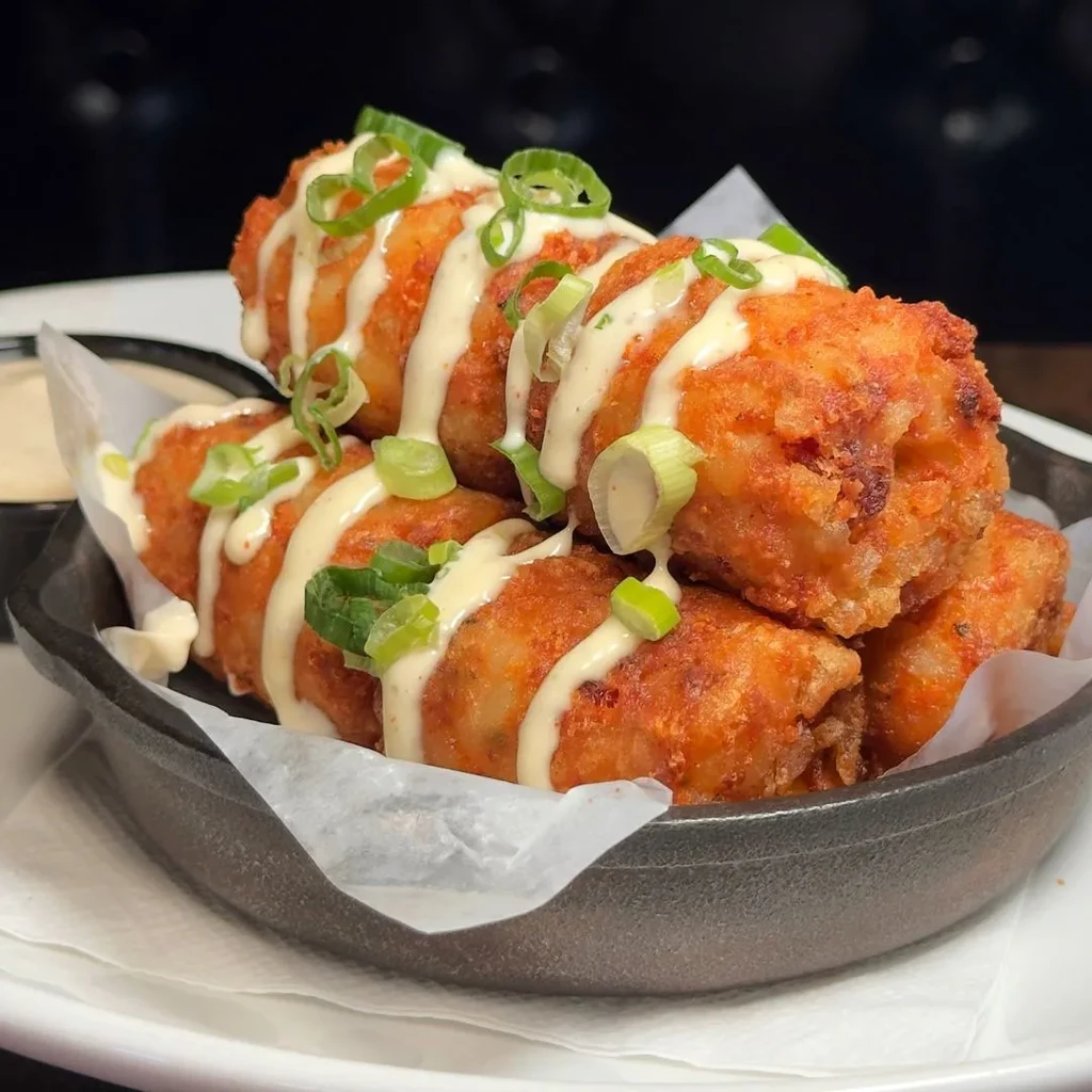 Crispy fried croquettes topped with creamy sauce and green onions.