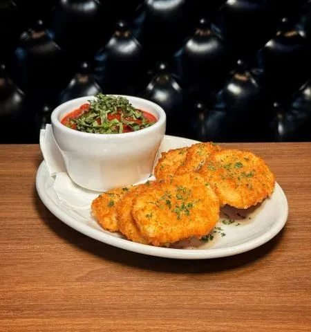 Golden-brown breaded items with marinara, parsley, and basil.