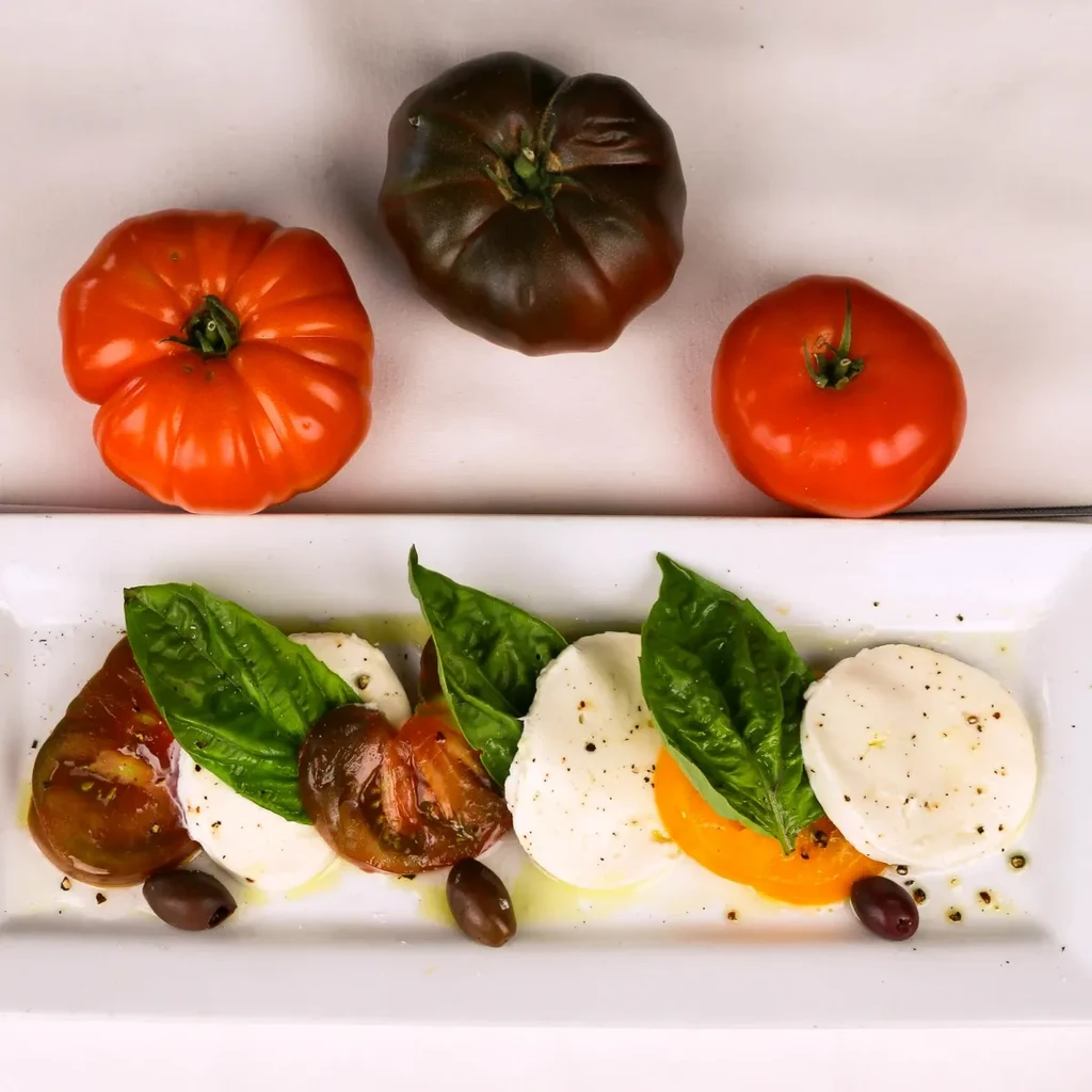 Colorful Caprese salad with heirloom tomatoes, mozzarella, basil, and whole tomatoes.
