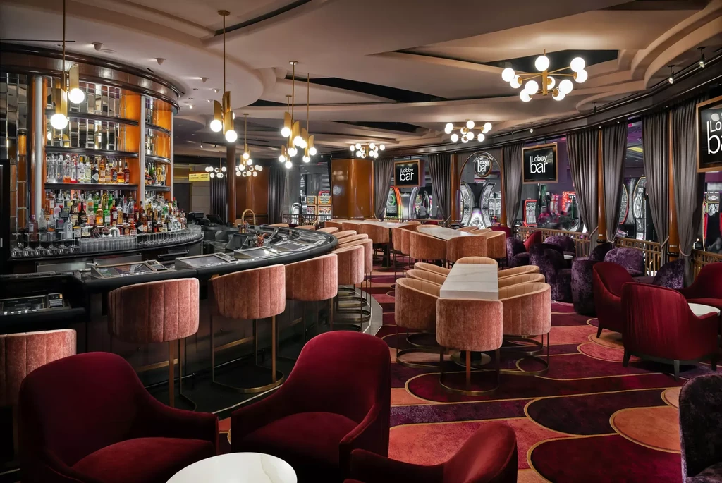 Modern, upscale lobby bar with pink velvet seating and casino games.