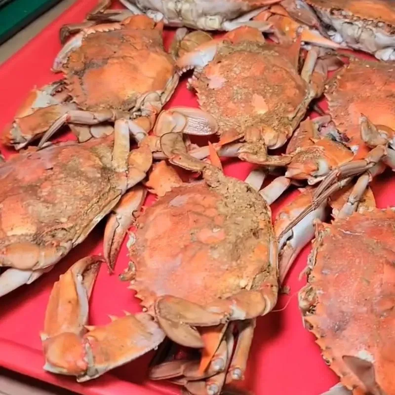 Close-up of multiple cooked crabs piled on red surface.
