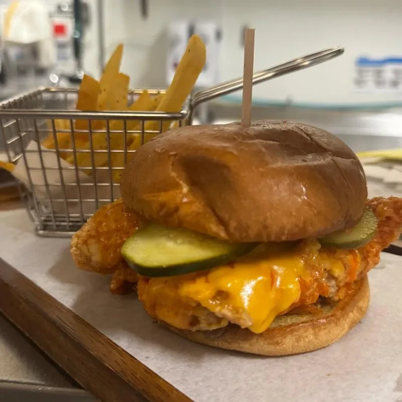 Crispy chicken sandwich with melted cheese, pickles, and french fries.