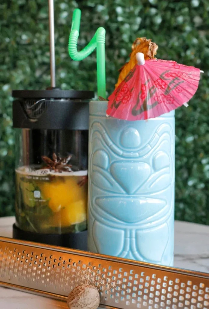 French press and blue tiki mug drinks, with nutmeg garnish.