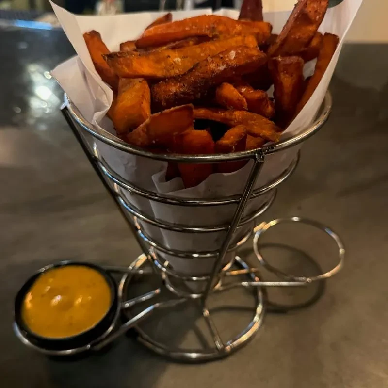 Crispy, salted sweet potato fries in a cone with dipping sauce.