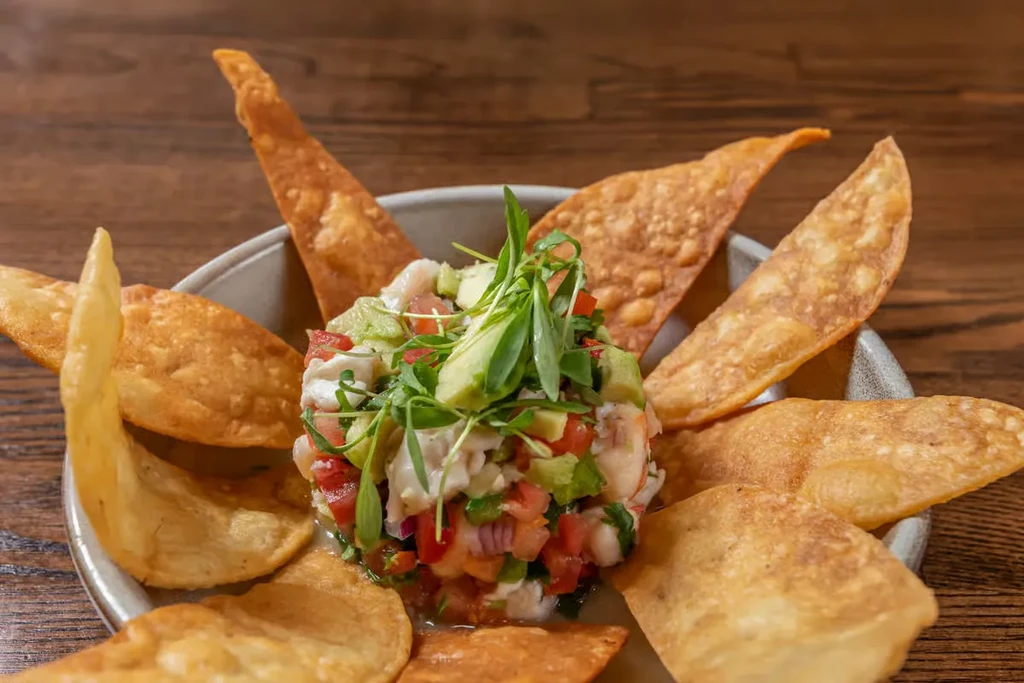 Close-up of vibrant ceviche with avocado, tomatoes, herbs, and tortilla chips.