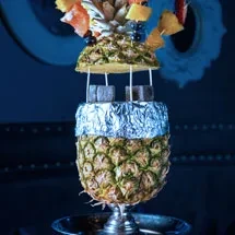 Decorative pineapple hookah with fruit bowl, charcoal, and ornate base.