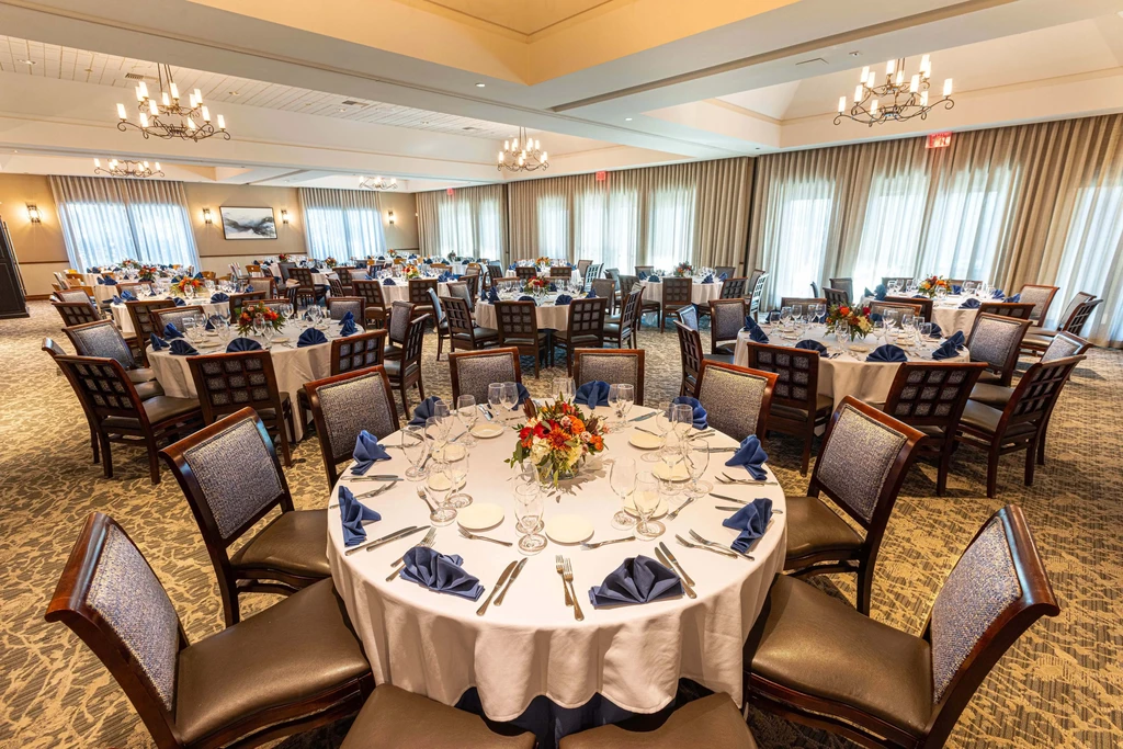 Empty, elegantly set banquet hall with tables, flowers, and chandeliers.