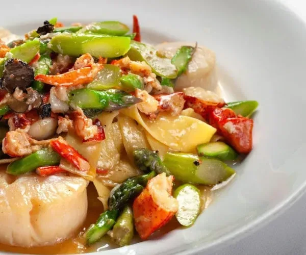 Gourmet pasta with lobster, scallops, asparagus, and mushrooms.