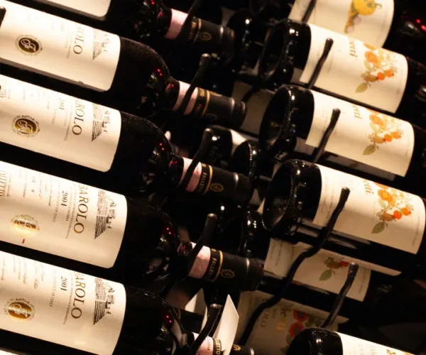 Multiple rows of Barolo and Pallini wine bottles in a rack.