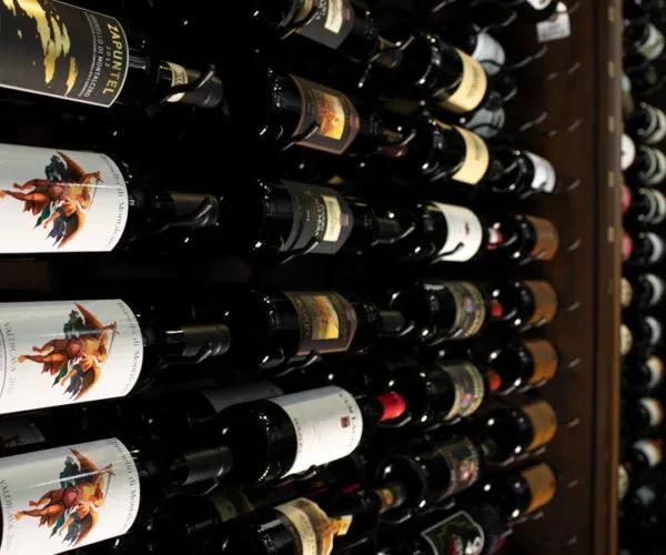 Close-up of dark Valdicava and Zapuntel wine bottles stacked in a rack.