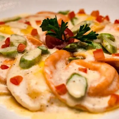 Creamy orange ravioli dish with diced tomatoes and fresh herbs.