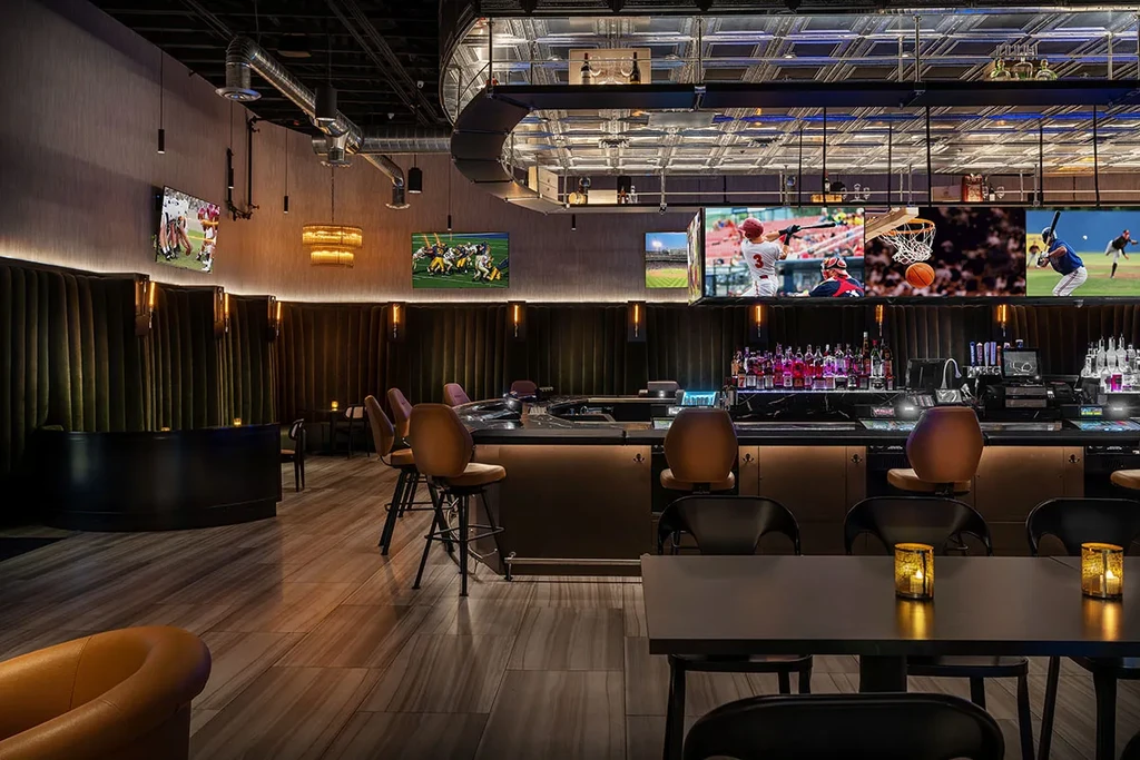 Modern sports bar: curved bar, olive booths, and numerous sports TVs.
