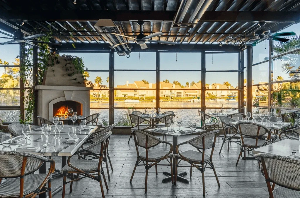 Elegant modern restaurant dining room with fireplace and water view.