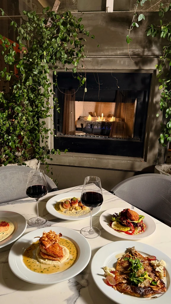 Plated dishes, wine, marble table, and fireplace in an upscale restaurant.