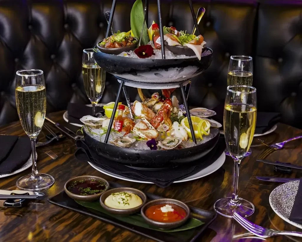 Multi-tiered seafood tower with oysters, crab, lobster, and champagne.