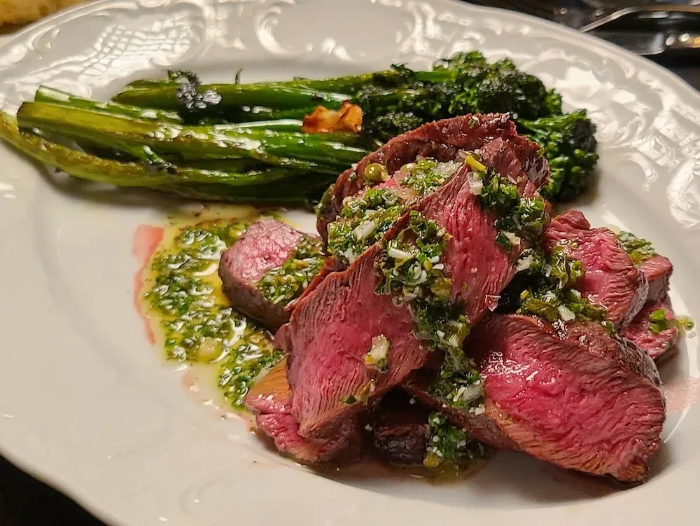 Seared steak with green chimichurri and grilled broccolini.