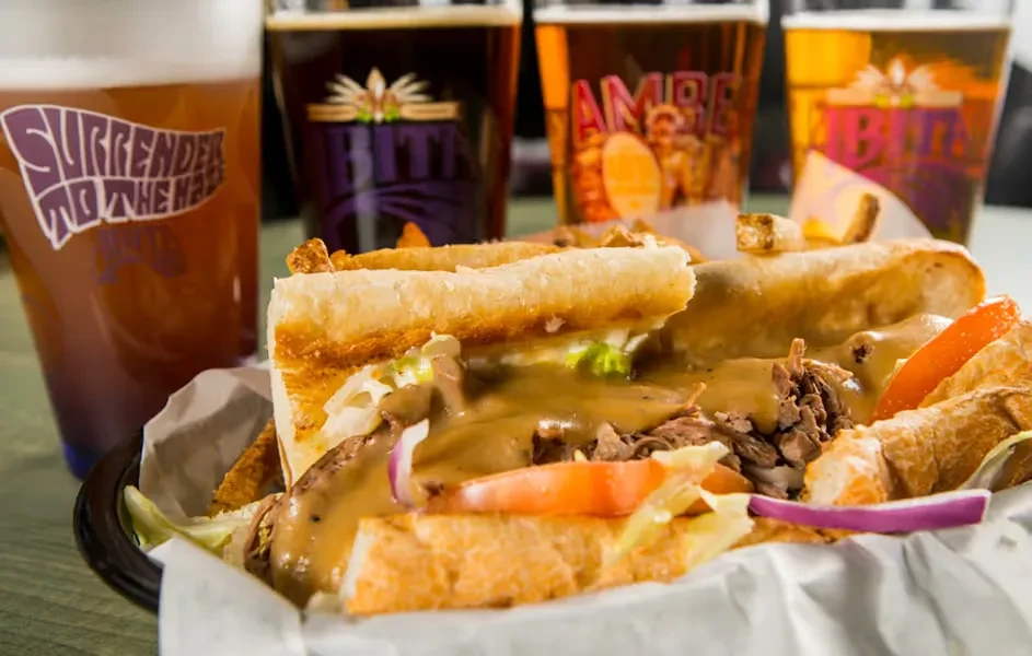 Large roast beef sub in a basket, with four craft beers.