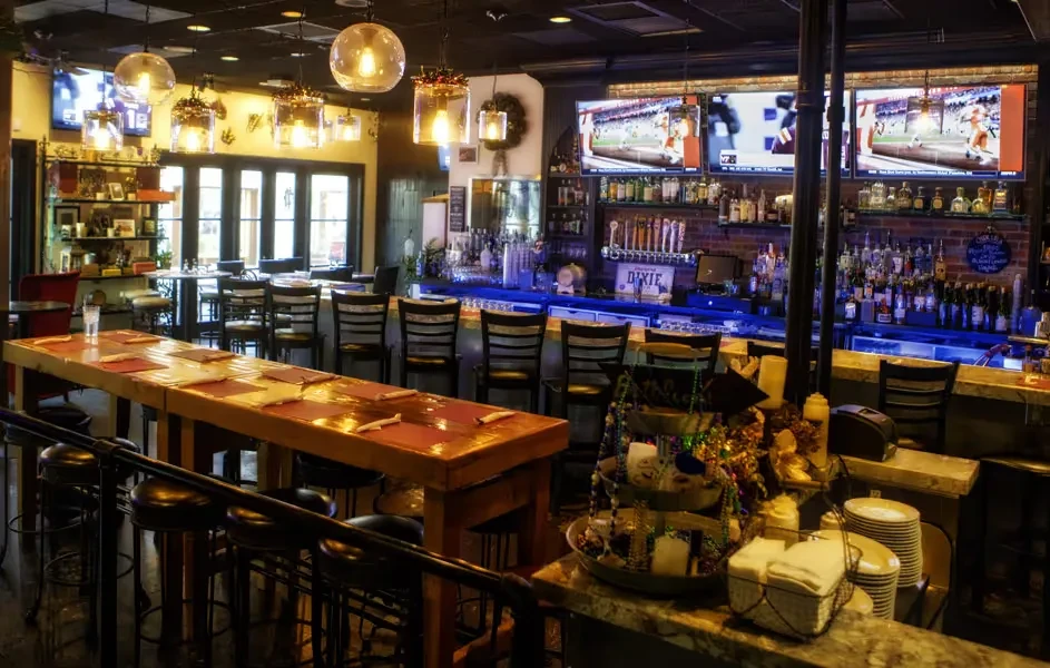 Empty restaurant and bar interior with sports TVs and Mardi Gras decor.