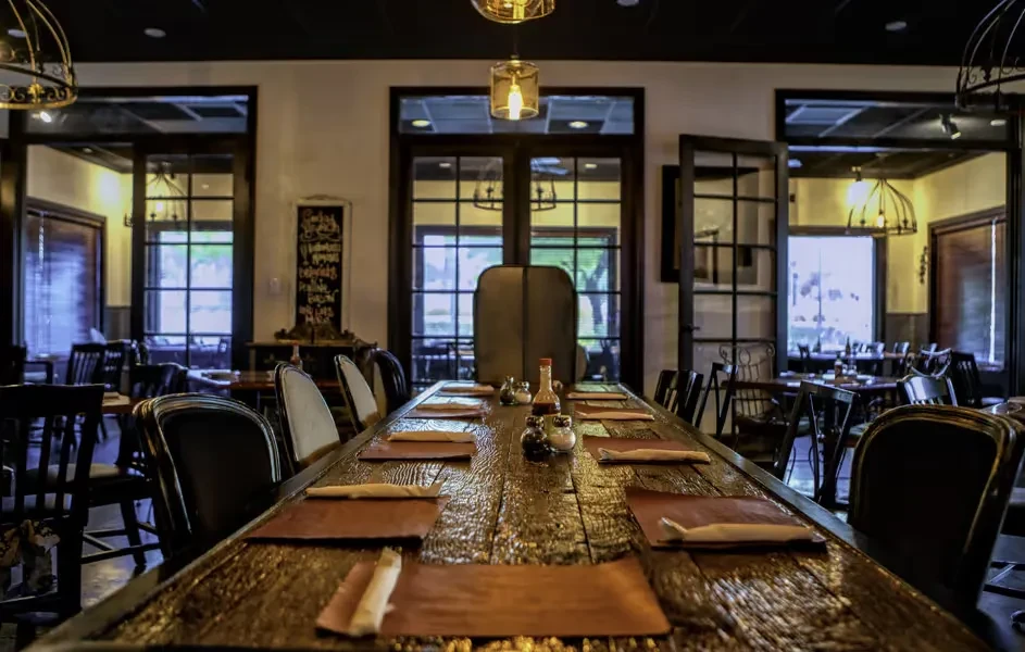 Long rustic wooden communal table set inside a warm restaurant.