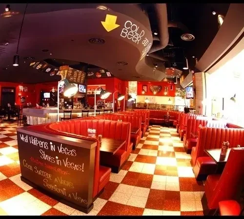 Empty retro diner interior with red booths and a checkered floor.