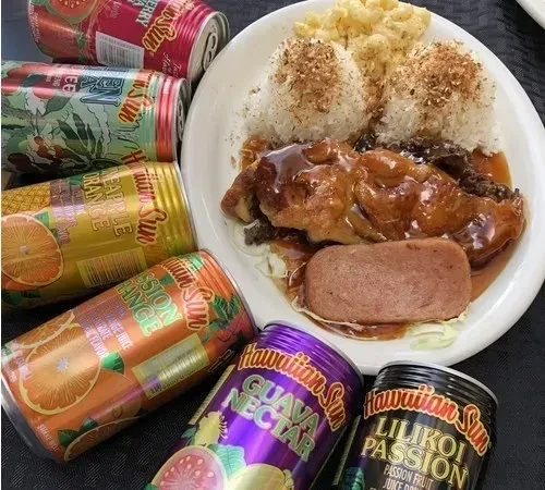 Plate lunch with Spam, rice, meat, macaroni salad, and Hawaiian Sun cans.