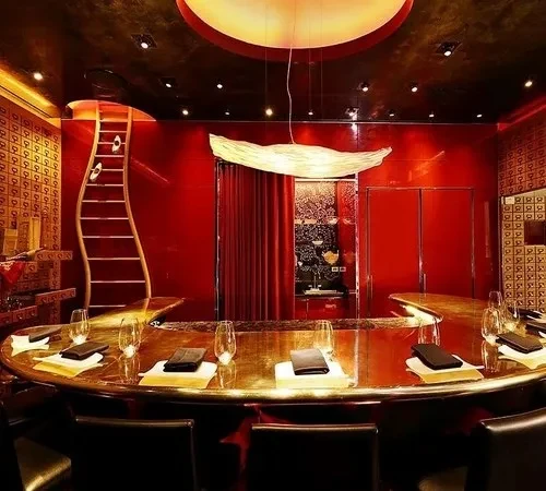 Curved golden table, red and gold restaurant interior with wavy staircase.