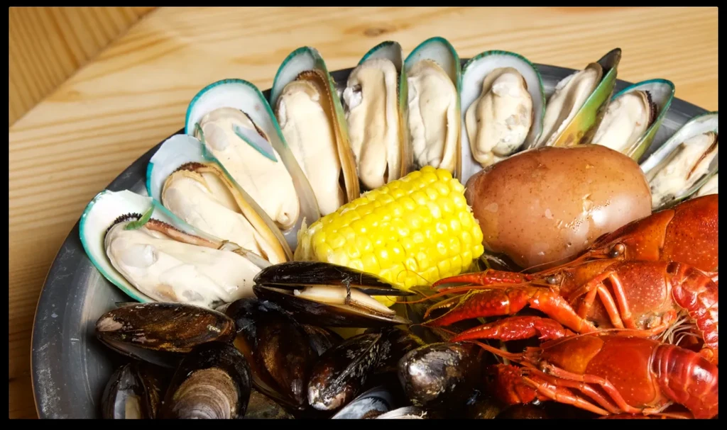 Seafood boil platter with mussels, crawfish, corn, and potato.
