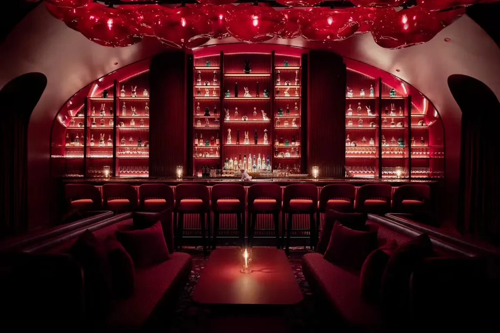 Dark red bar with well-stocked counter, high stools, and glowing glass ceiling.