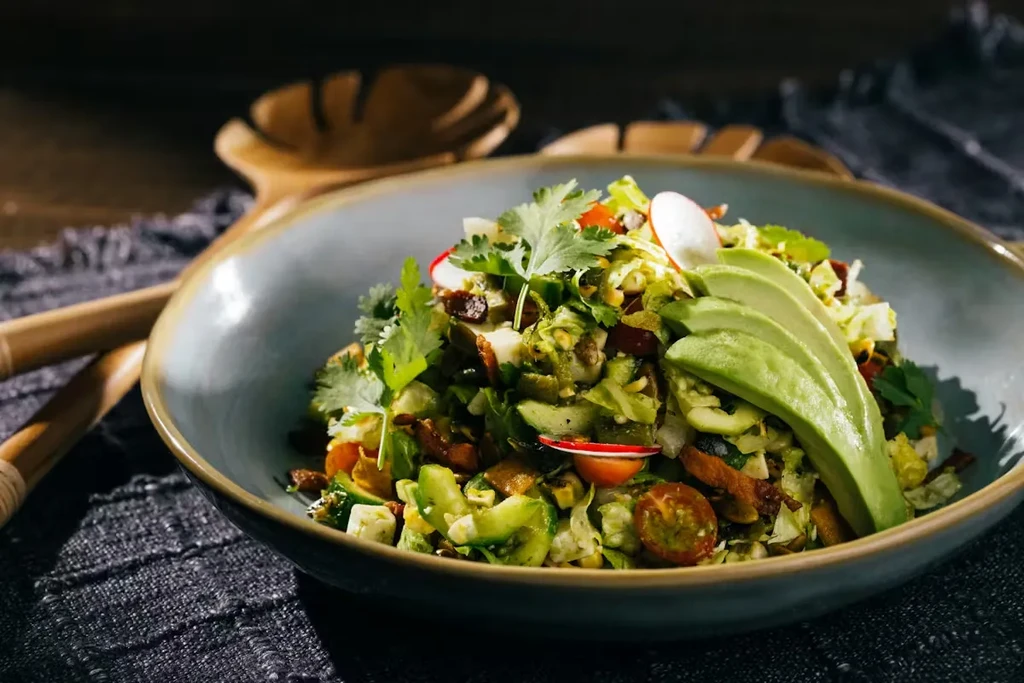 Vibrant salad in a rustic bowl with avocado, tomatoes, and cilantro.