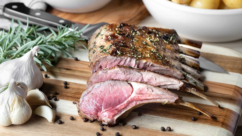 Roasted, sliced medium-rare rack of lamb with herbs, garlic, peppercorns.