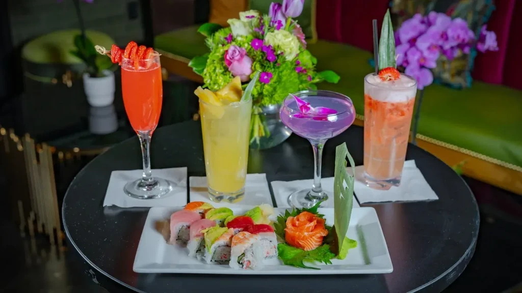 Colorful sushi platter and four cocktails in a sophisticated restaurant.