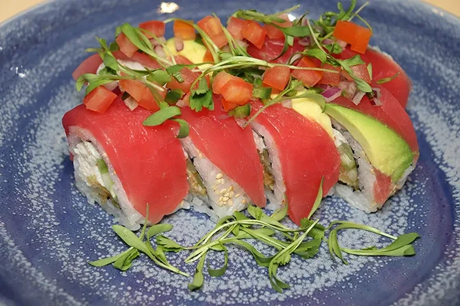 Six sushi rolls with tuna, avocado, tomato, onion, and microgreen topping.