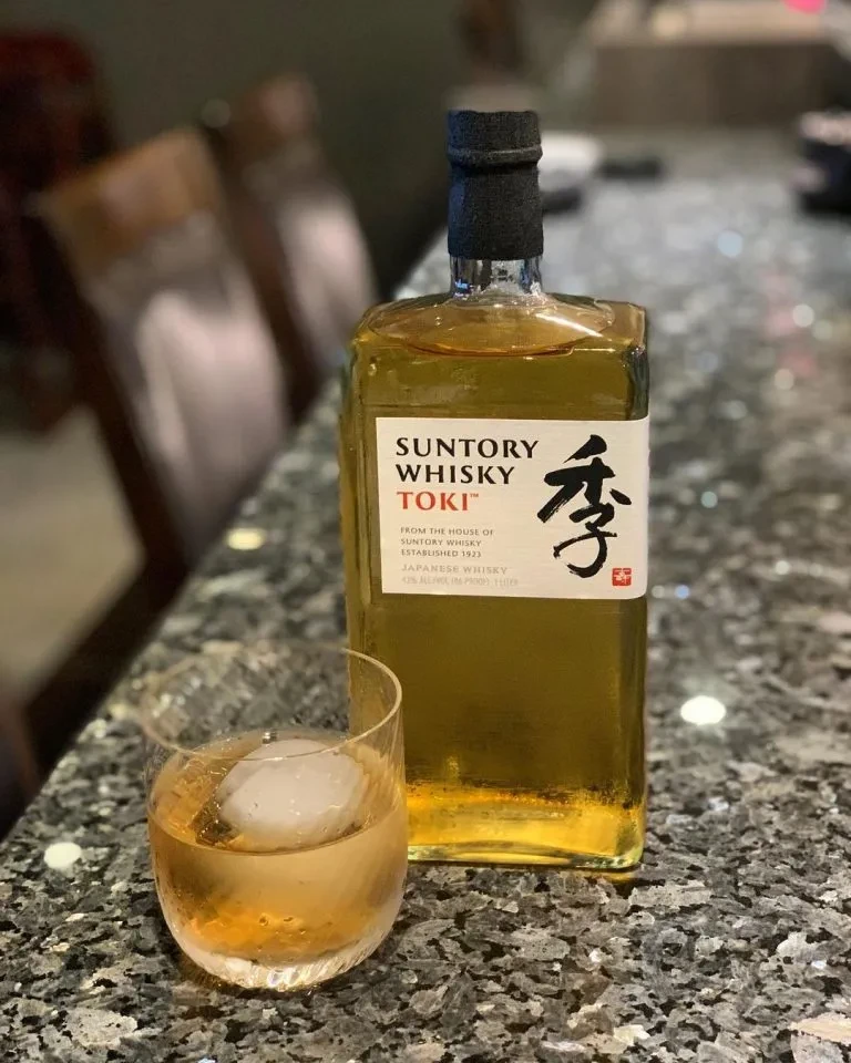 Suntory Whisky Toki bottle and glass with spherical ice cube on granite.