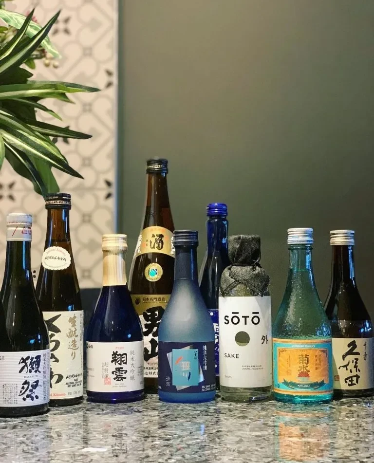 Ten diverse Japanese sake bottles displayed on a reflective countertop.