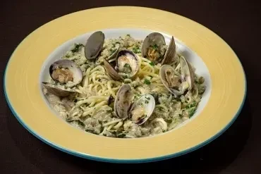 Dish of pasta with clams, herbs, served in a yellow-rimmed bowl.