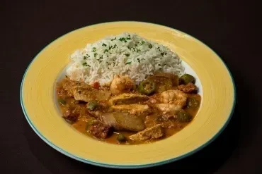 Hearty stew with shrimp, fish, okra, and rice on a yellow plate.