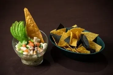 Seafood ceviche with avocado and a bowl of mixed tortilla chips.