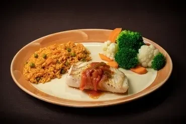 Fish with tomato sauce, orange rice, and steamed vegetables on a plate.
