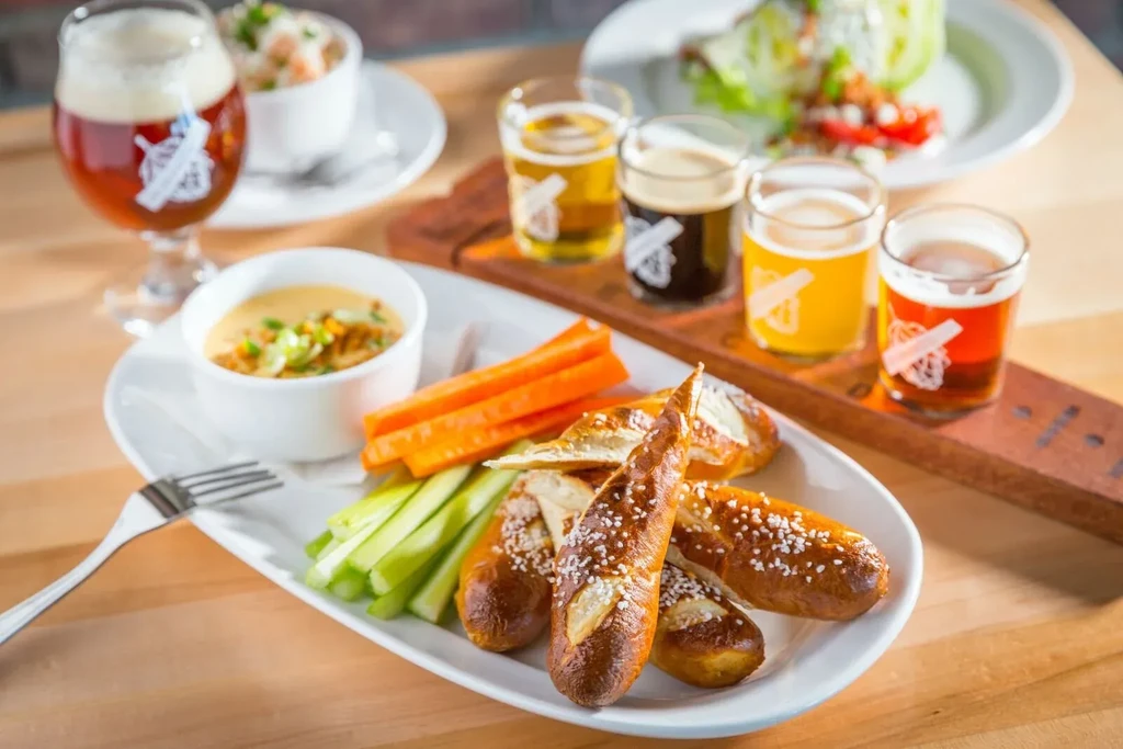 Platter of soft pretzels, cheese dip, vegetables, and a beer flight.